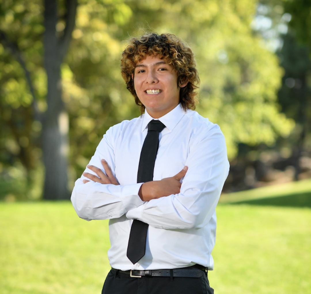 professional photo of Damian, smiling, in a white shirt and a black tie